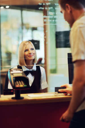 Ticket for two. A beautiful woman dressed in uniform sitting in a ticket booth serving a male...