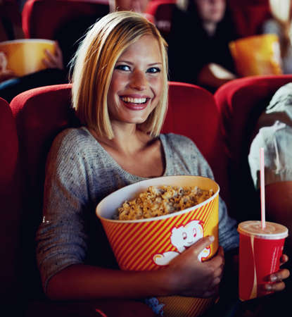 Movie magic. A portrait of a happy young girl holdng a tub of popcorn and a cold drink in her hands...