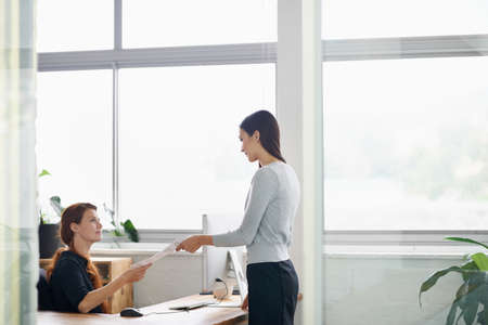 Let me know if there are any changes to be made. Shot of a young businesswoman handing her colleague...