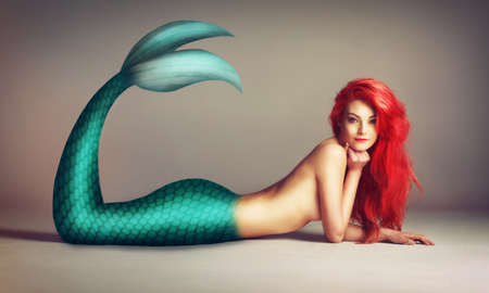 Shes a catch. Shot of a beautiful red-headed mermaid lying down.の写真素材