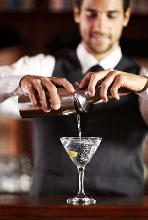 Shaken not stirred. Shot of a handsome young bartender mixing a cocktail.