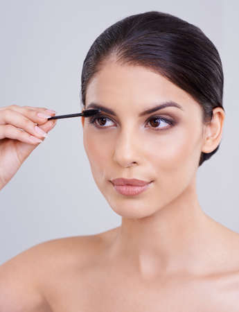 Adding to her natural beauty. Shot of a beautiful young woman applying mascara to her lashes.