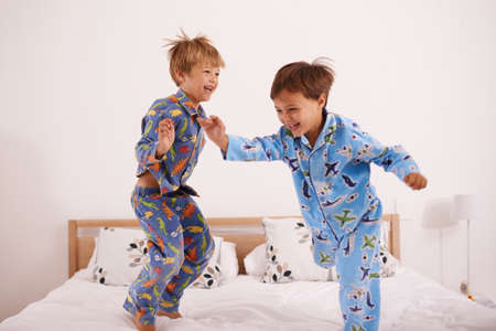 Weve got the moves likes jagger. Shot of two little boys jumping on the bed.