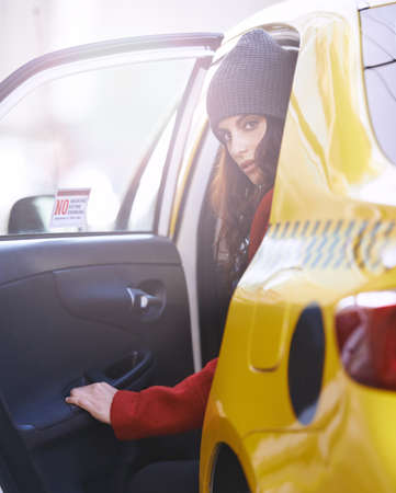 On the move in the city. Portrait of a fashionable young woman getting into a cab in the city.の写真素材