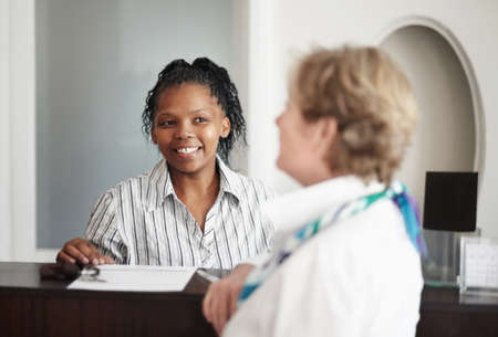 Diligent, friendly assistance. A receptionist giving a senior woman the keys to her hotel room.