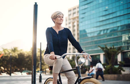 You cant go wrong when youre going forward. Shot of a mature businesswoman traveling with a bicycle through the city.の写真素材