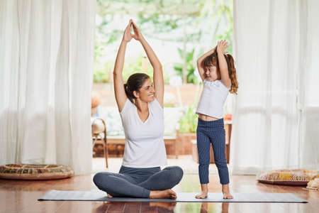 Youre getting there my child. Shot of a focused young mother and daughter doing a yoga pose together...