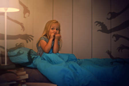 Afraid of the monsters lurking in the shadows. Shot of a frightened little girl being kept awake by...