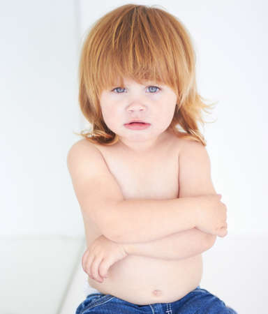 Shes feeling grumpy. A cute baby looking miserable with her arms folded.の写真素材