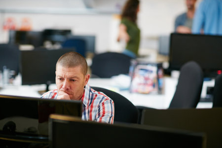 He knows the importance of hard work. Shot of a man using a computer in a modern office.の写真素材