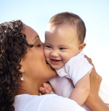 Happy times. Closeup of a young mother holding up and kissing her baby daughter.の写真素材
