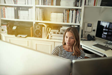 She makes technology work for her. Shot of a young woman working on a computer in her home office.