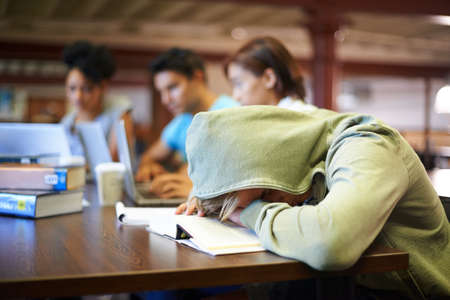 Feeling the strain of looming exams. A young student in a study group suffering from the exhaustion of finals.の写真素材