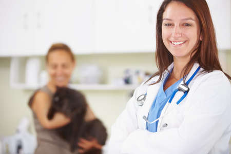 Another happy pet owner. A portrait of a smiling female vet with a pet owner and her cat int he...