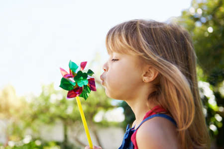 All i need to have fun.... Shot of a cute little girl playing with a pinwheel outside.の写真素材