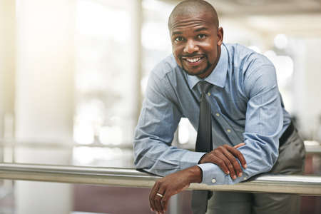 Corporate confidence. Cropped portrait of a businessman leaning against a railing in the office...