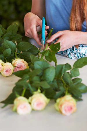 Shes learned the skills necessary for great arranging. High angle shot of a florists hands trimming...