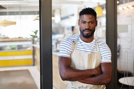 We make seriously good coffee in here. Portrait of a handsome young man standing at the entrance to...