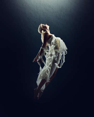Imagination sets her free. A beautiful young woman floating in the air isolated against black.