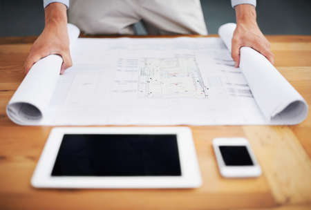 Rolling out the plans. Cropped image of an architect going over his blueprints.