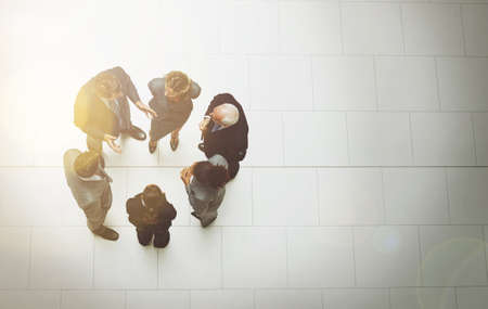Talking in the lobby. High angle shot of a group of businesspeople talking in the office lobby.の写真素材