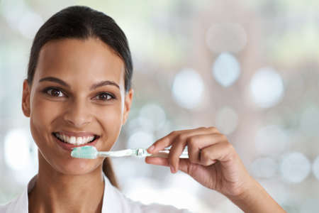 Brush everyday for a perfect smile. Portrait of a smiling woman holding a toothbrush.の写真素材