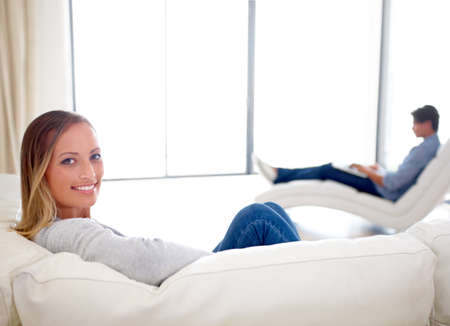 Enjoying a quiet day at home. A pretty young woman relaxing in the lounge with her boyfriend in the...