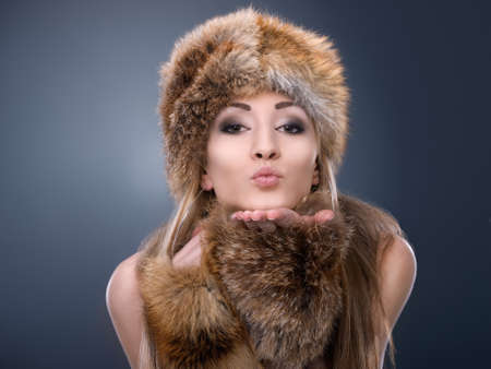 Sending you some warm love. Portrait of a woman dressed in fur blowing a kiss.
