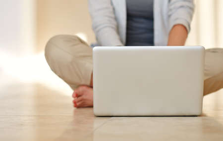 Wireless freedom in the home. Cropped shot of a woman using a laptop while sitting on her living room floor.の写真素材