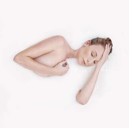 Smooth as silk. Studio shot of an attractive woman submerged in a white liquid.