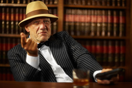 He heads up a large criminal organisation. Aged mob boss wearing a hat and looking serious while pointing.の写真素材