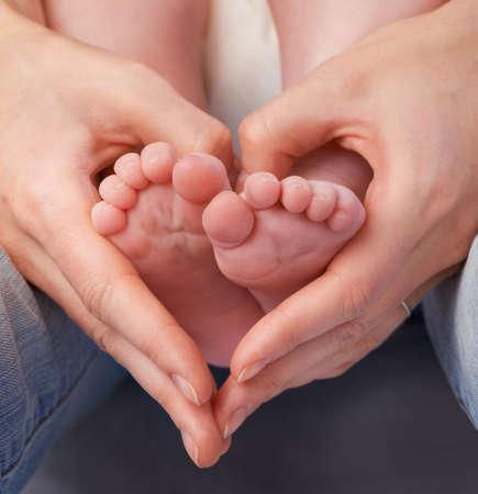 Loving the little things. Cropped shot of a mothers hands making a heart shape around her babys...