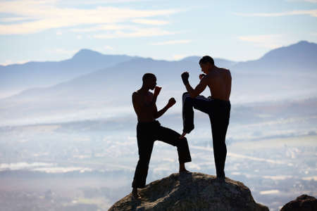 Extreme kickboxing. A male kickboxer practising their technique on a mountain peak.の写真素材