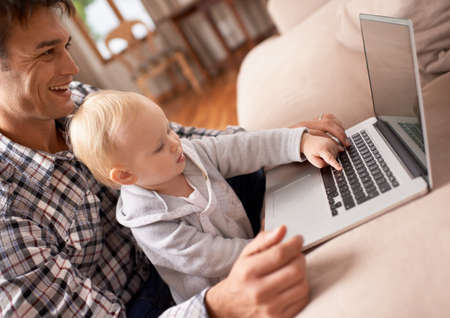 Showing dad how its done. A young father showing his baby girl how to use a laptop.の写真素材