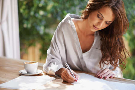 Shes going to become a famous writer. Shot of an attractive young woman writing in a relaxed...