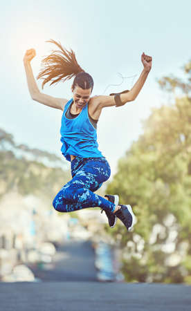 Hard work never goes unnoticed. Shot of a young woman jumping in mid air after her workout.の写真素材
