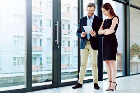 So this is what Ive been working on.... Full length shot of two businesspeople talking in the office.の写真素材