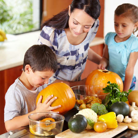 I think its ready. Shot of a mother helping her children carve pumpkins for halloween.の写真素材