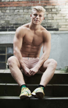 Fit and confident. Shot of a muscular young man sitting on a staircase.の写真素材