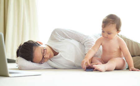 Motherhood can be exhausting. An exhausted young mother lying asleep on the floor with her baby...