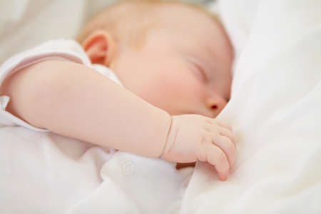 Baby in dreamland. A baby girl fast asleep in between her white pillows.の写真素材