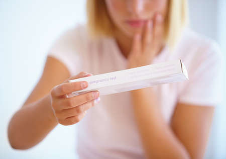 She needs to take the test. A young woman looking nervous about taking a pregnancy test.