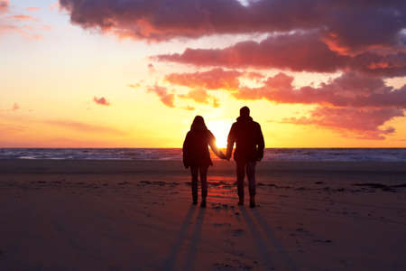 Shadows in the sunset. Silhouette of a couple going for a walk on the beach at sunset.