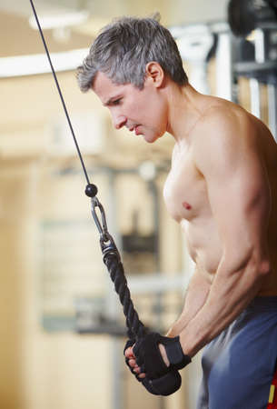 Focussed on stamina. A shirtless man working out at the gym.