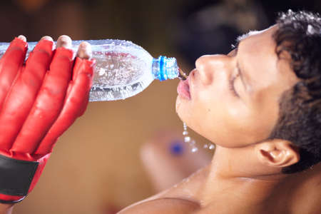Keeping himself hydrated. A high angle view of a young fighter drinking from a bottle of water.