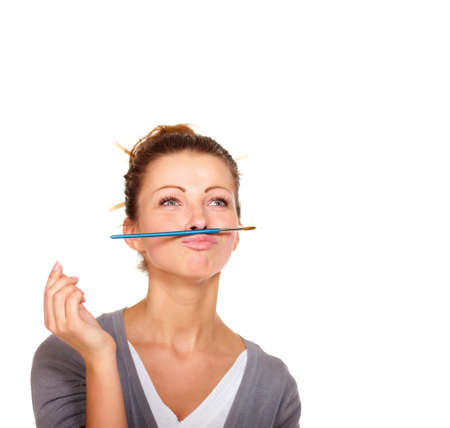 Inspiration is hard to come by. Studio shot of an attractive woman balancing a paint brush on her upper lip.の写真素材