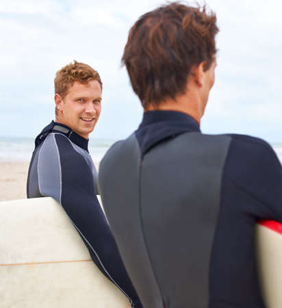 Bonded by their love of surfing. Two young surfers standing on the beach with the ocean in the...