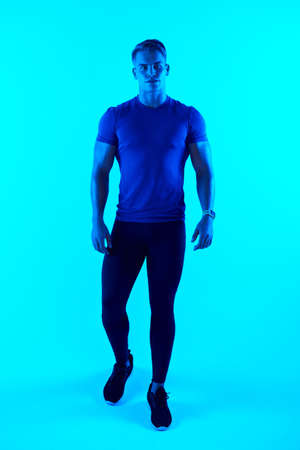 Its about putting one foot in front of the other. Studio portrait of a handsome young male athlete posing against a blue background.の写真素材