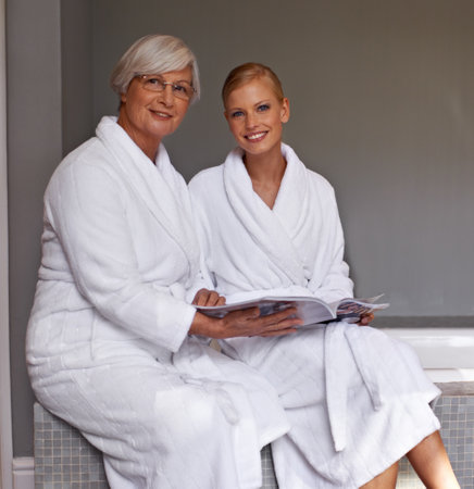 Discussing the brides big day. Grandmother and granddaughter flipping through a magazine.の写真素材