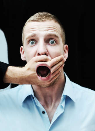 I will not be silenced. A distraught looking man with his mouth showing through the hand trying to silence him.の写真素材